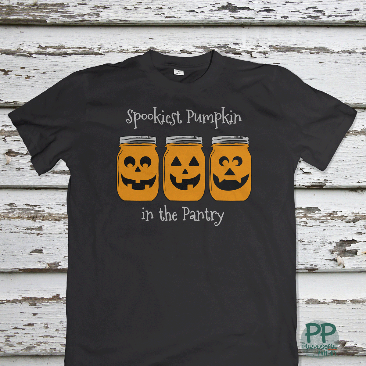 The Printify Toddler Tee Halloween Spookies Pumpkin in the Pantry features three pumpkin faces in jars and festive text—perfect for little ones' Halloween fun.