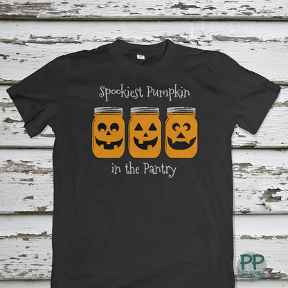 The Printify Toddler Tee Halloween Spookies Pumpkin in the Pantry features three pumpkin faces in jars and festive text—perfect for little ones' Halloween fun.