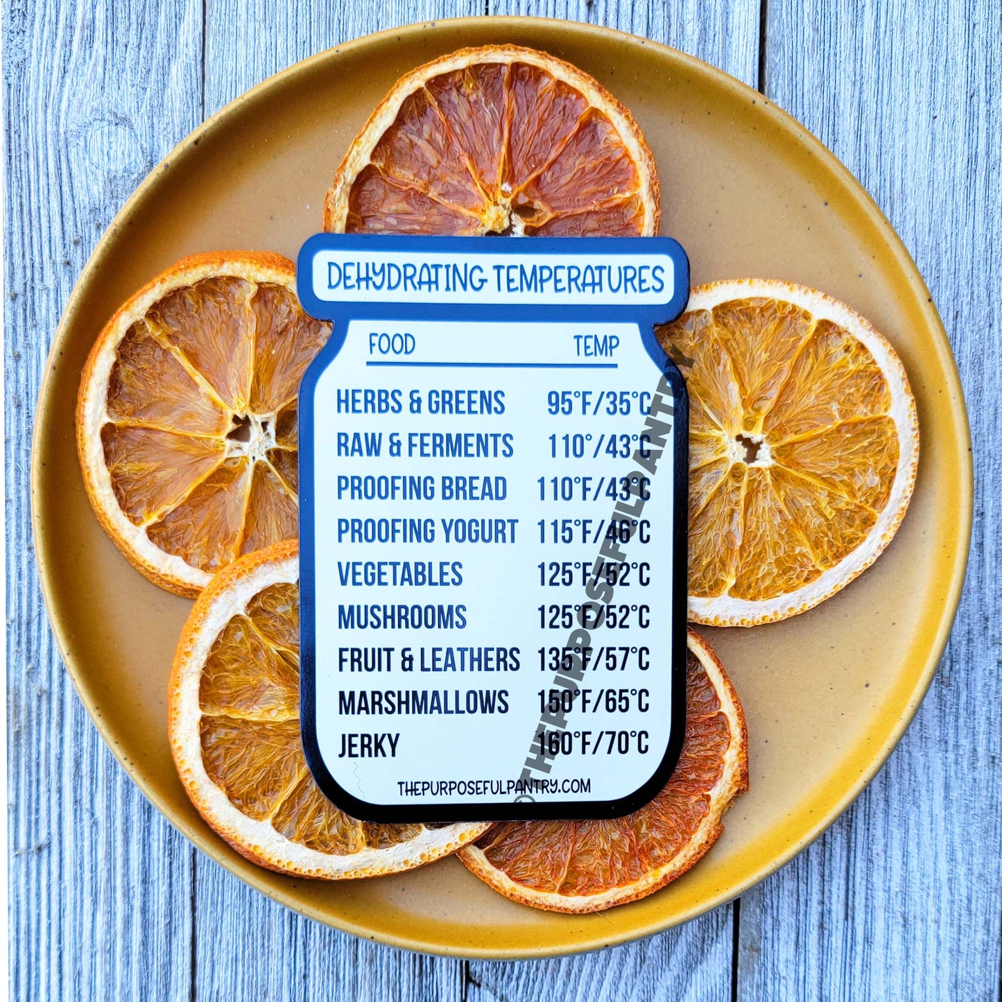 A plate of orange slices with The Purposeful Pantry's Dehydrating Temperature Guides & Checklist label on it.
