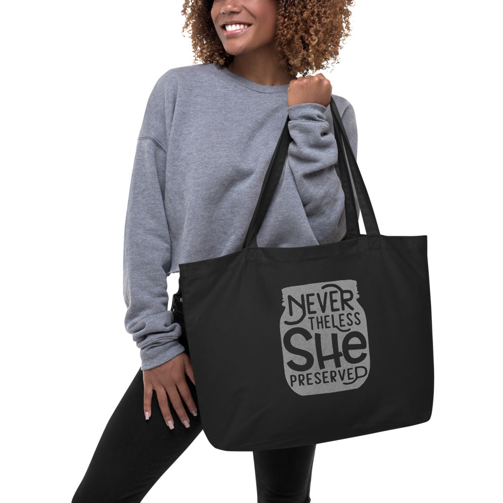A woman holding a black large organic tote bag from The Purposeful Pantry with the words never let her go.